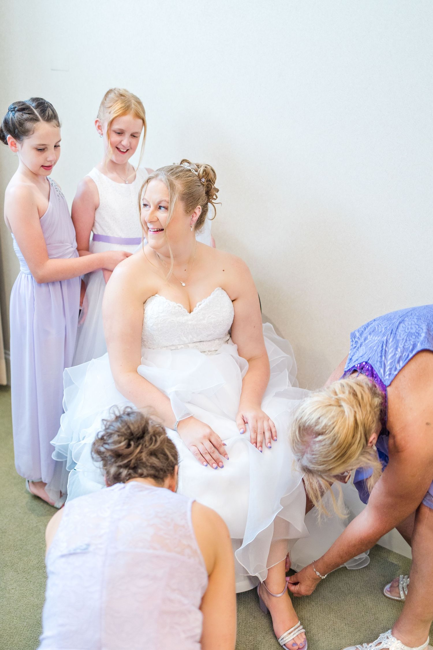 Wedding party helping the bride with final adjustments to her dress before the ceremony.