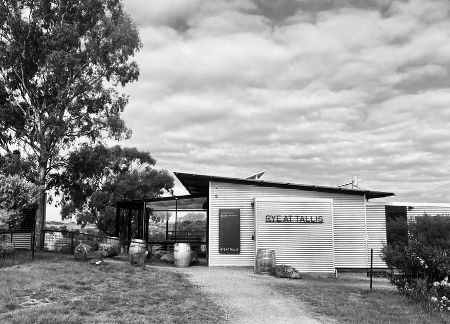 A rustic black and white photograph of a small rural building with eucalyptus trees.