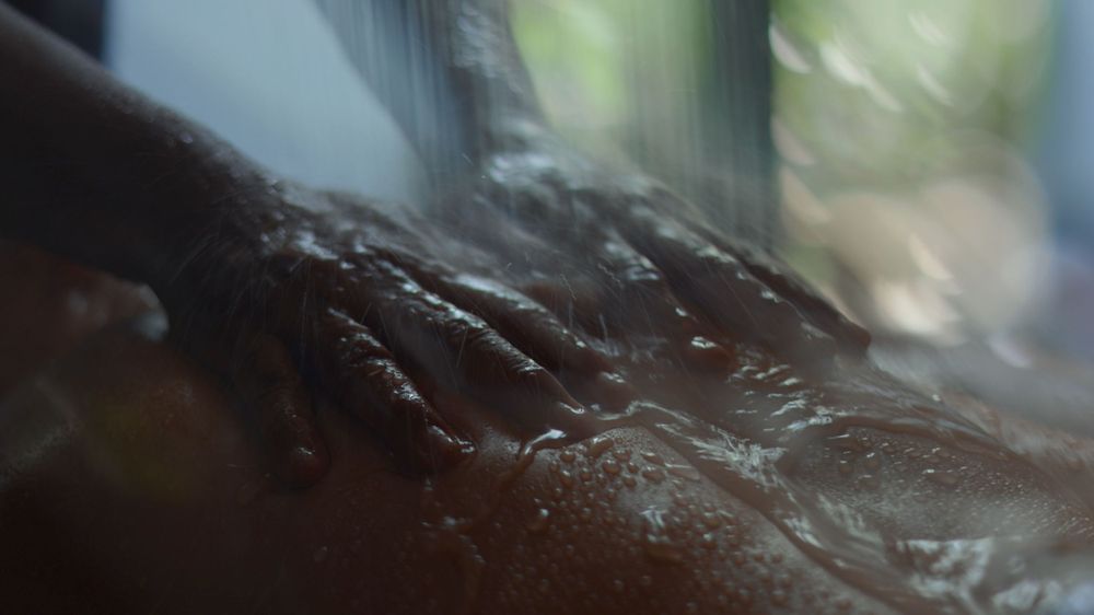 Close-up macro shot of dark wet surface with blurred background and water droplets.