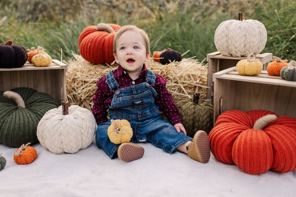 Autumn photo scene with overalls, pumpkins and hay bales creates harvest setting.