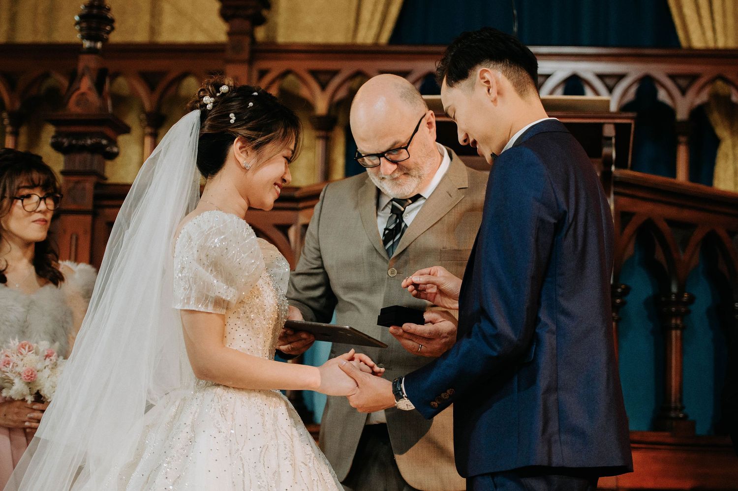 A wedding ceremony in a historic church with ornate wooden details and golden lighting.