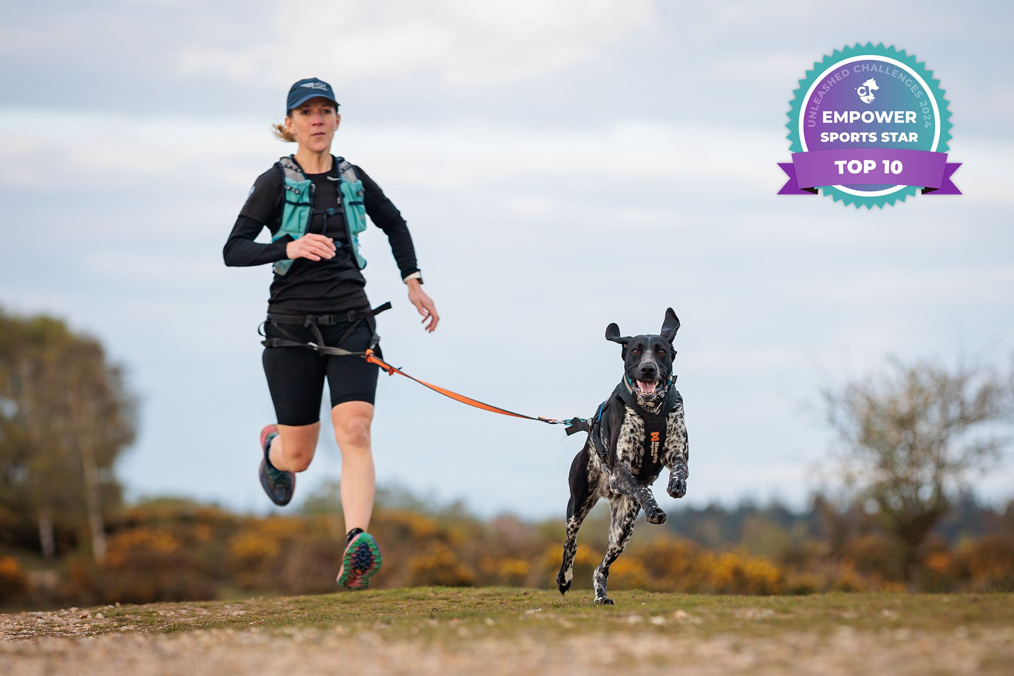 A dog and companion canicross running together on a trail in dynamic action.