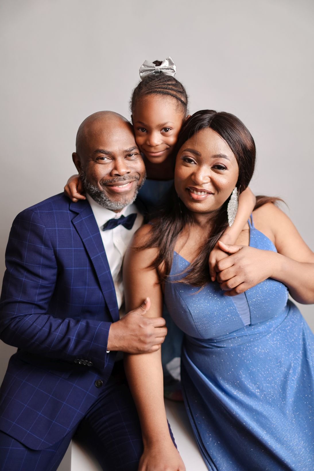 Family of three sharing a happy candid moment together during a studio photoshoot.