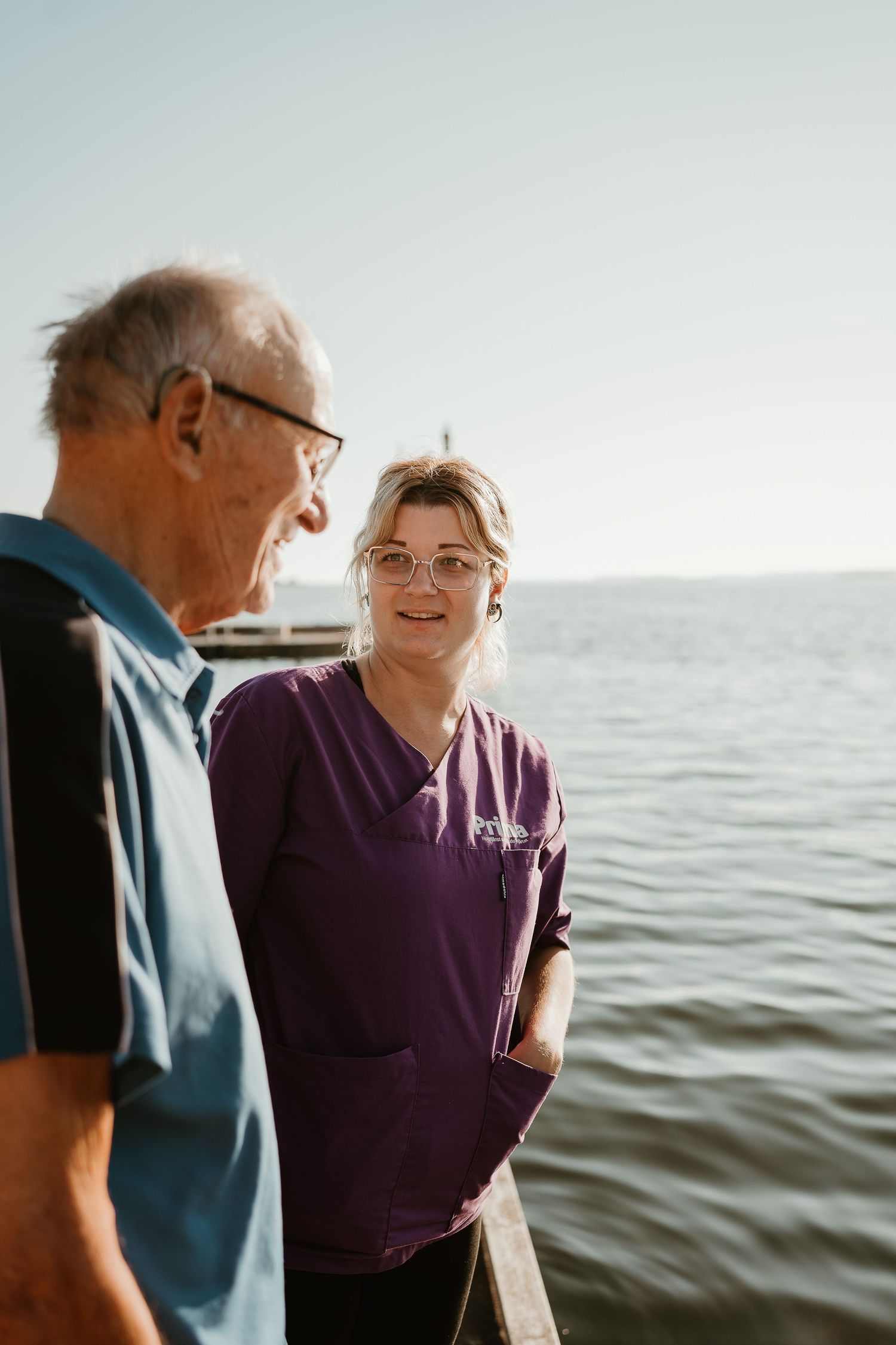 Healthcare professionals having a conversation by waterfront on sunny day.