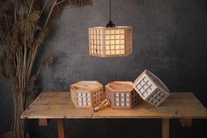 Wooden hexagonal pendant lamps displayed on rustic table with dried pampas grass decoration.