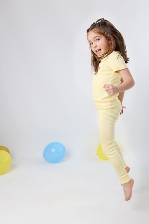 Yellow outfit against white backdrop with colorful balloons.