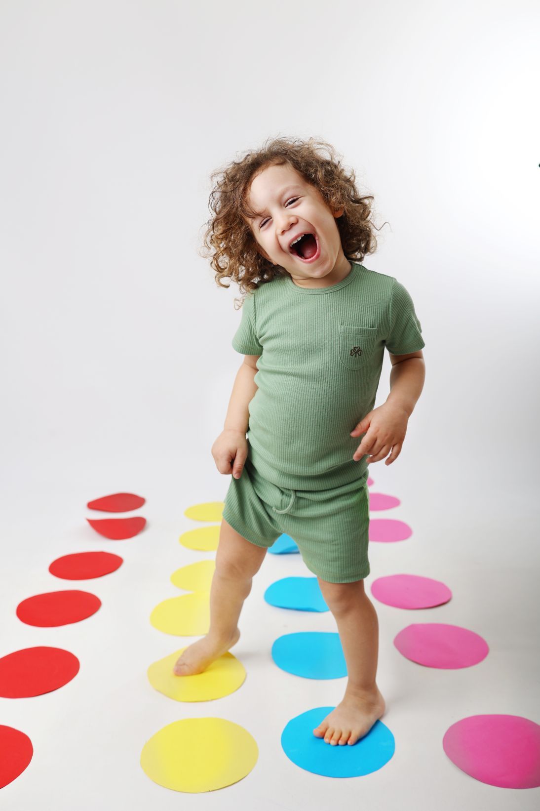 A playful moment on a colorful dot pattern floor against white backdrop.