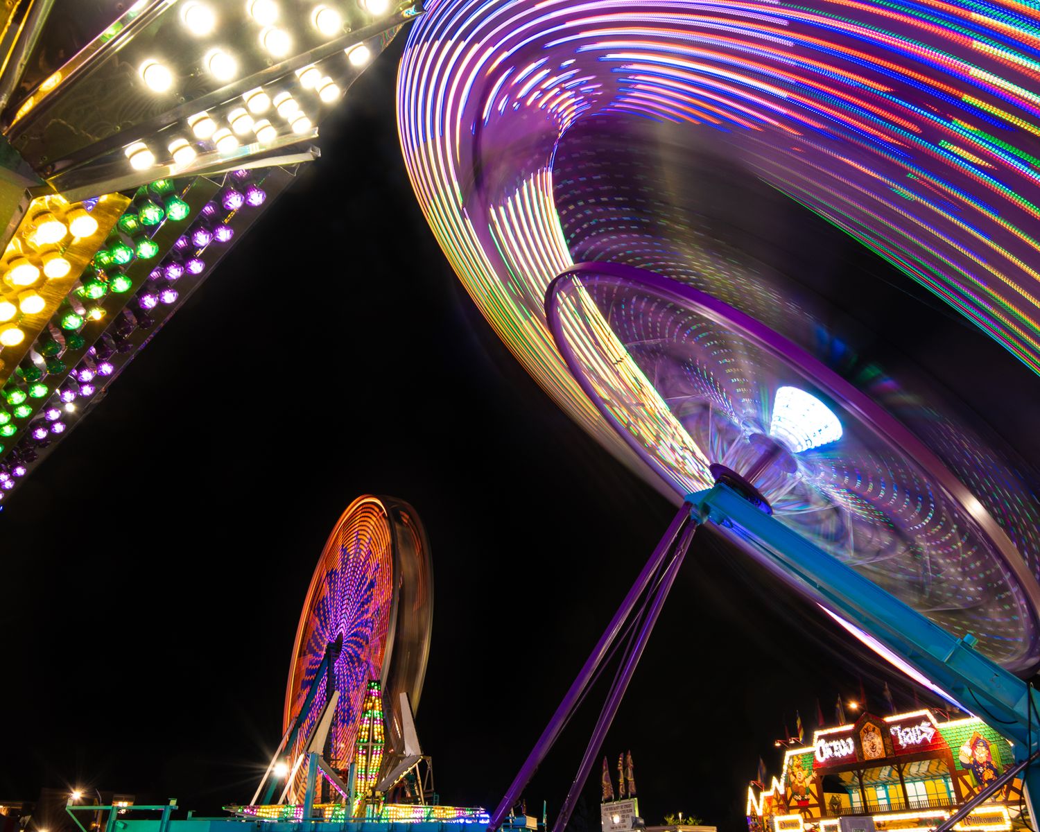 Colorful carnival rides lit up at night with spinning neon lights and motion blur in this landscape photo in Middletown NJ