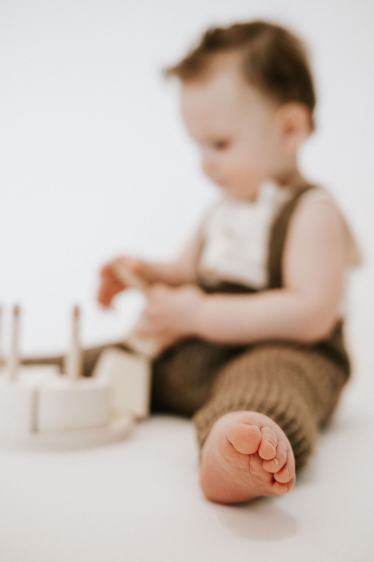Soft focus image of toddler's foot in foreground while playing with toys.