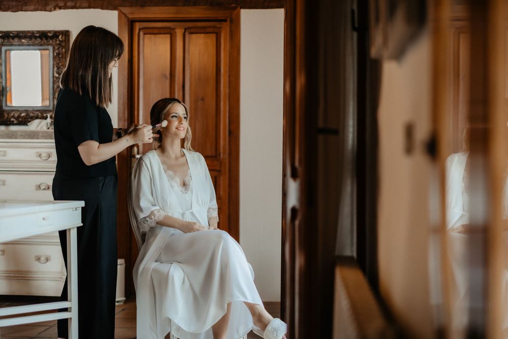 Bride getting ready for wedding day with help from bridesmaids in elegant hotel room.