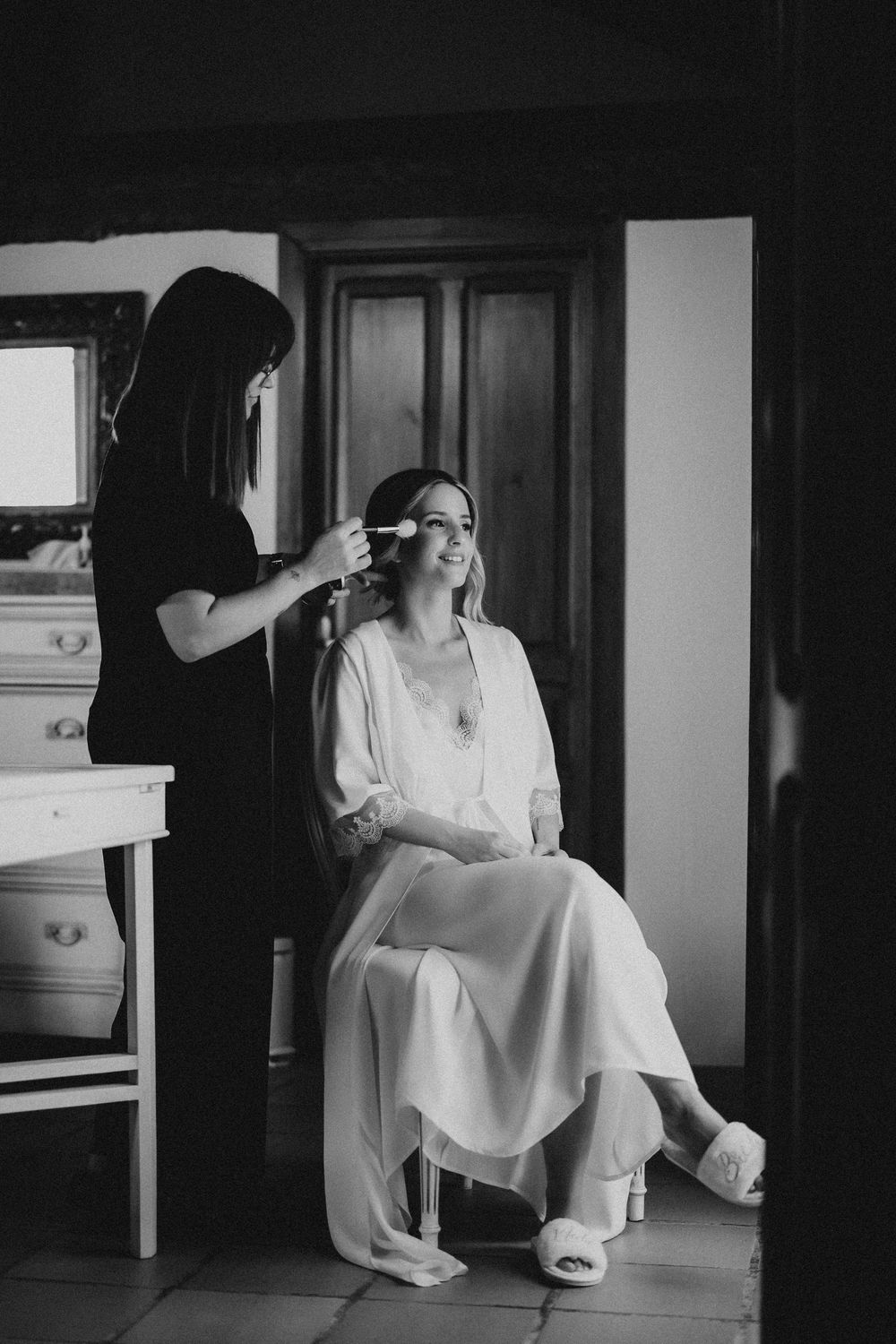 A series of black and white photographs showing someone in a white dress sitting on furniture in a dark room.