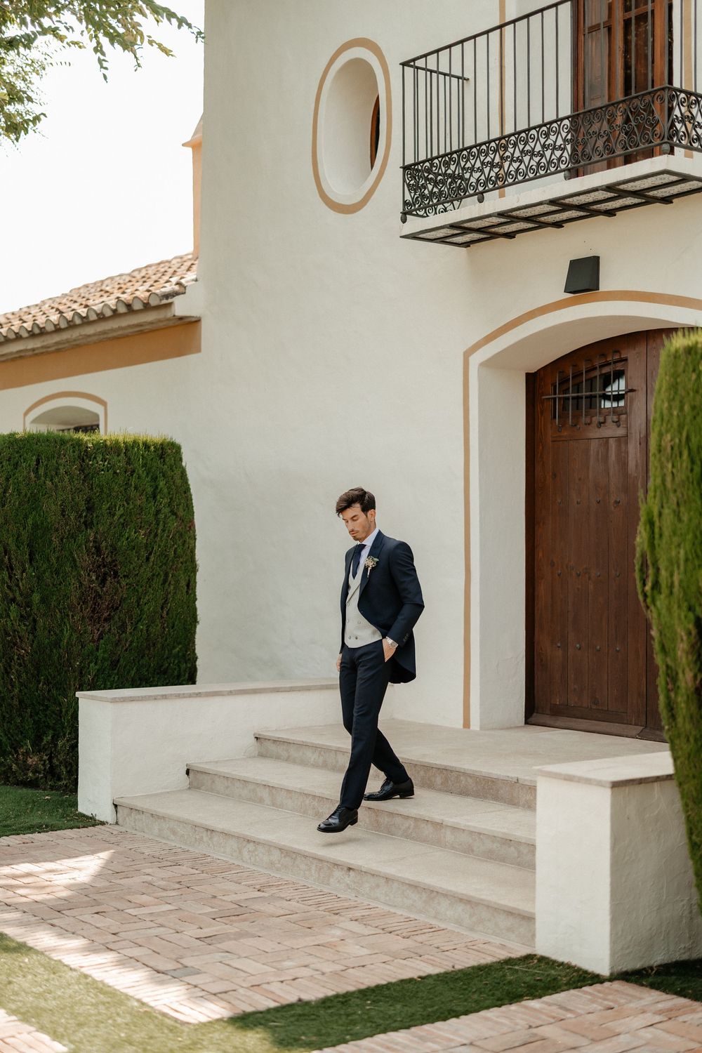 A sequence of photos showing a person in a dark suit walking down white concrete steps with green shrubs nearby.