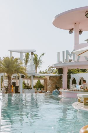 A luxurious resort pool with palm trees and modern white architecture.