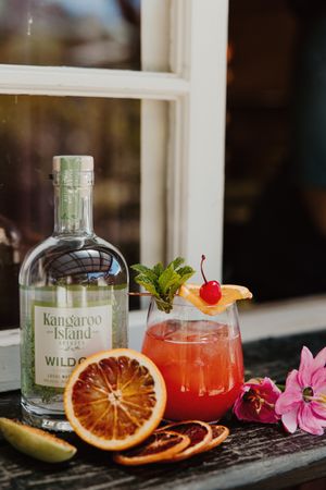 A craft cocktail with blood orange garnish and Kangaroo Island spirits bottle on a windowsill.