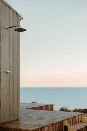 An outdoor shower deck overlooking the ocean with wooden planks and minimalist design.