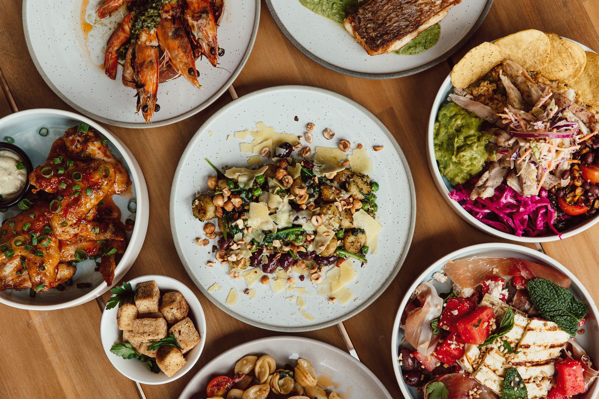 An overhead view of various colorful dishes and plates on a wooden table.