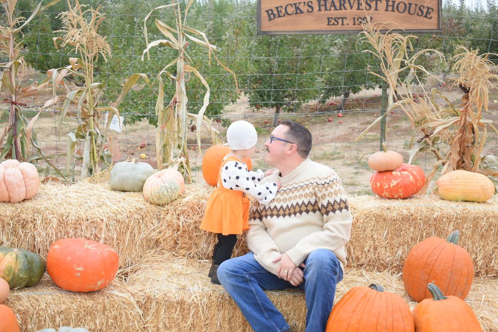 Seasonal pumpkin display with hay bales at a harvest house farm setting.