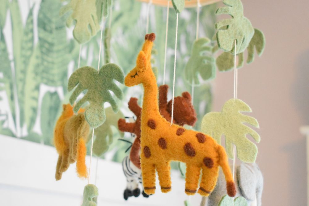 Handmade felt safari animal decorations including a spotted giraffe hanging from strings.