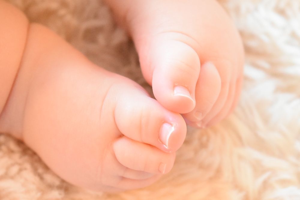 Close-up of tiny baby toes on soft beige textured fabric.