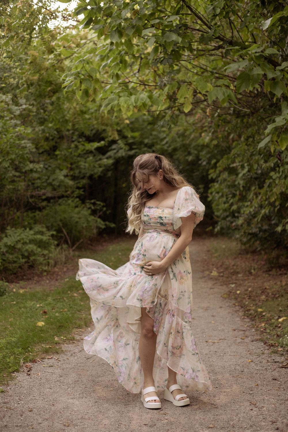 A woman enjoying her pregnancy playing with her dress in the forest