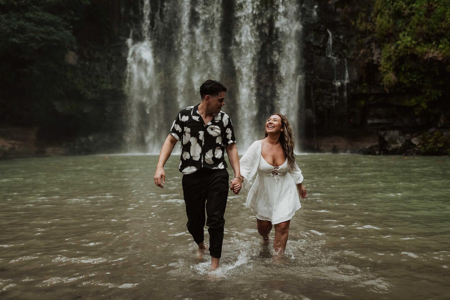 Couple running in front of a waterfall during their Costa Rica photo session