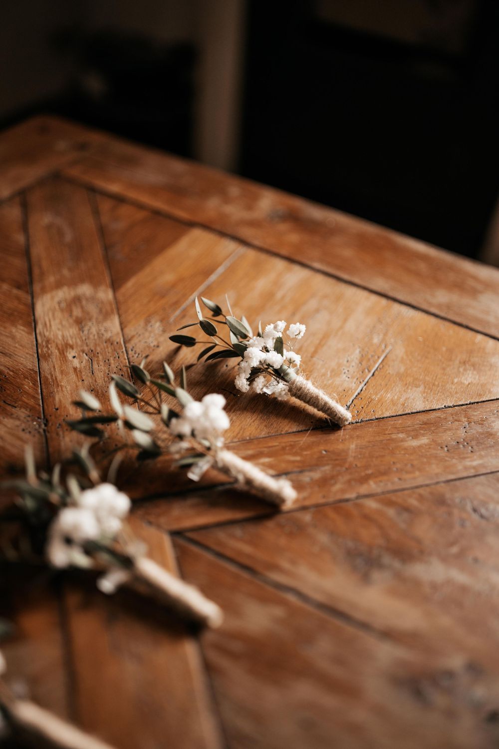 Delicate white floral boutonnieres arranged on a wooden surface.