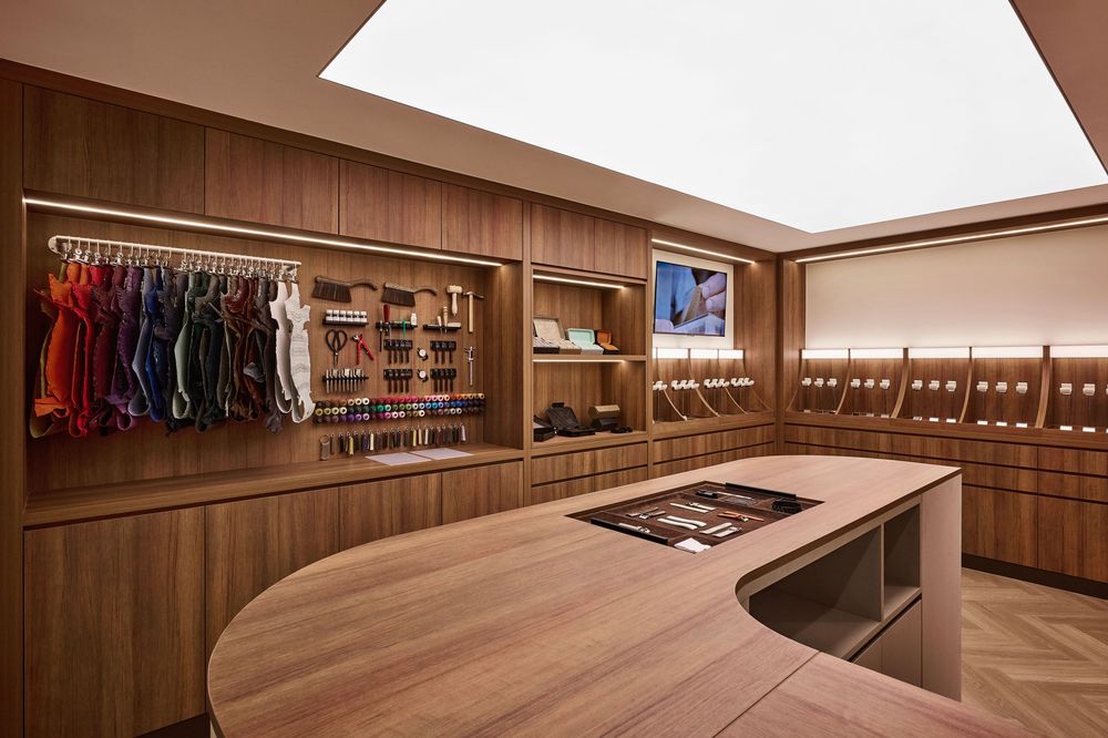 Upscale boutique interior featuring walnut wood island counter, colorful clothing rack, and built-in shelving with skylight.