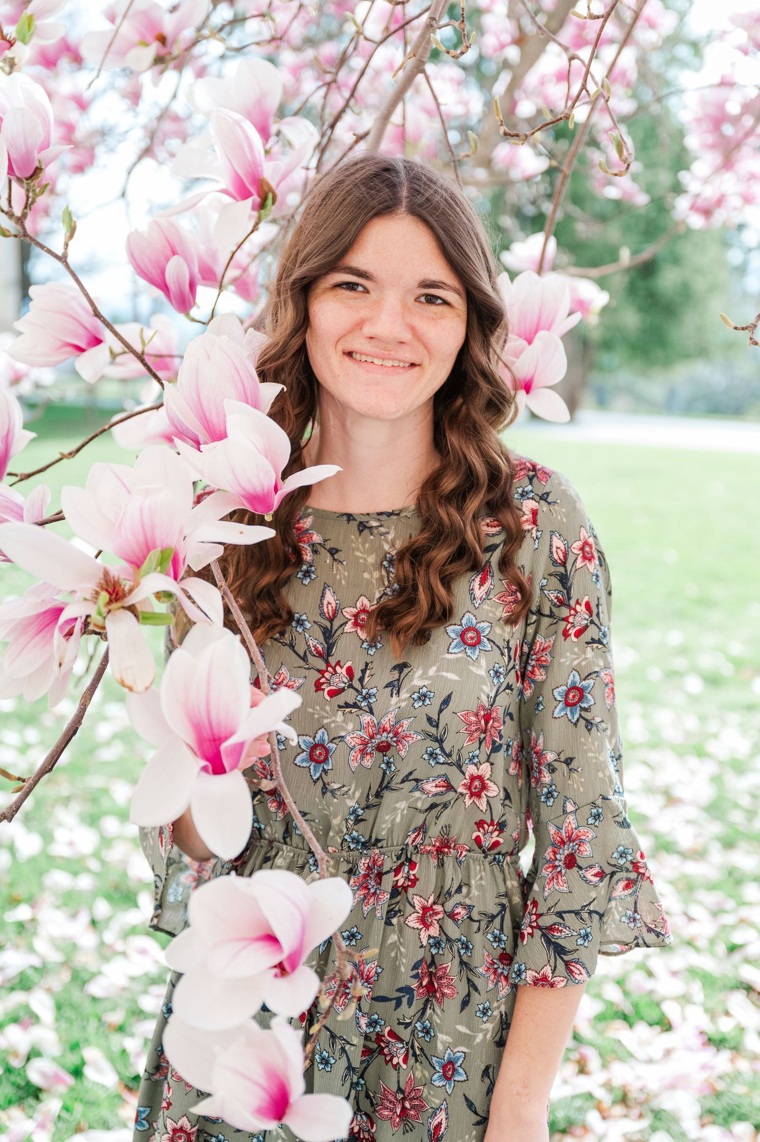 Portrait against beautiful pink magnolia blossoms in spring garden.