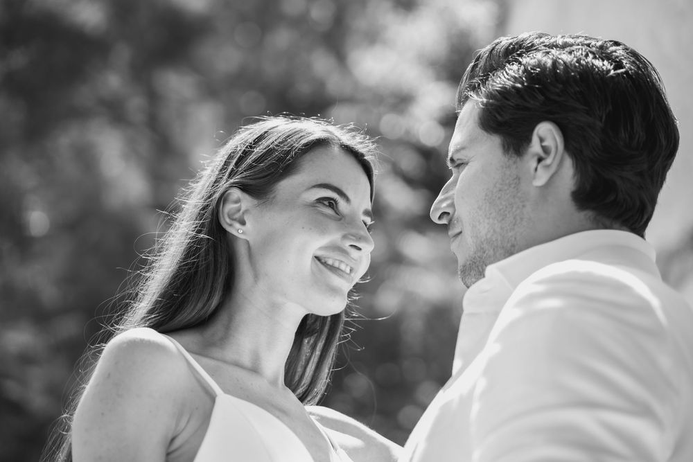 A romantic black and white photo of a couple sharing an intimate moment on a terrace.