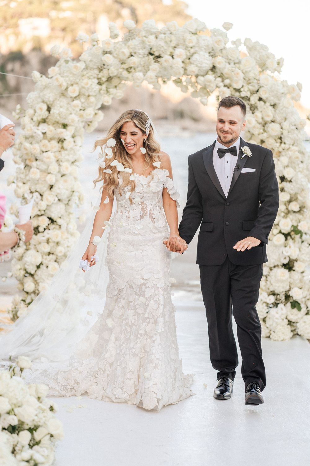 Newlyweds share joyful moments on their wedding day surrounded by elegant white floral arrangements and decor.
