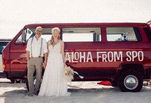 Red vintage Volkswagen van with 'Aloha From SPO' text parked on beach setting for wedding photoshoot.