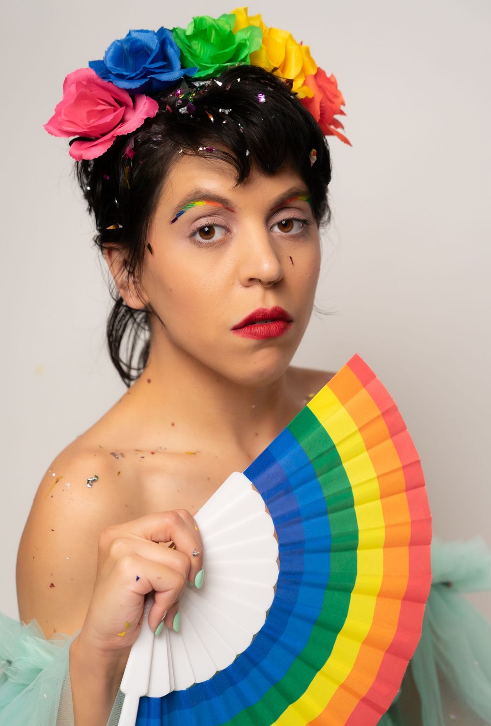 Colorful portrait series featuring a mint green tulle dress and rainbow fan against white backdrop with vibrant makeup.