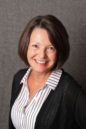 Professional headshot wearing striped shirt and black cardigan.