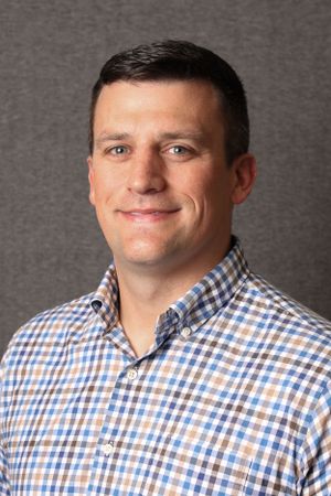 Professional headshot wearing checkered button-down shirt.
