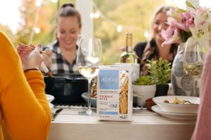 Friends enjoying dinner with wine and a bottle of Malicious Women Co. product on the table.