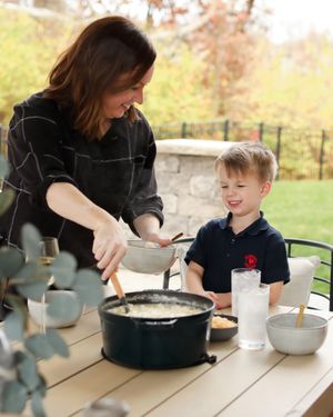 Outdoor cooking scene on wooden deck with bowls and cooking equipment.