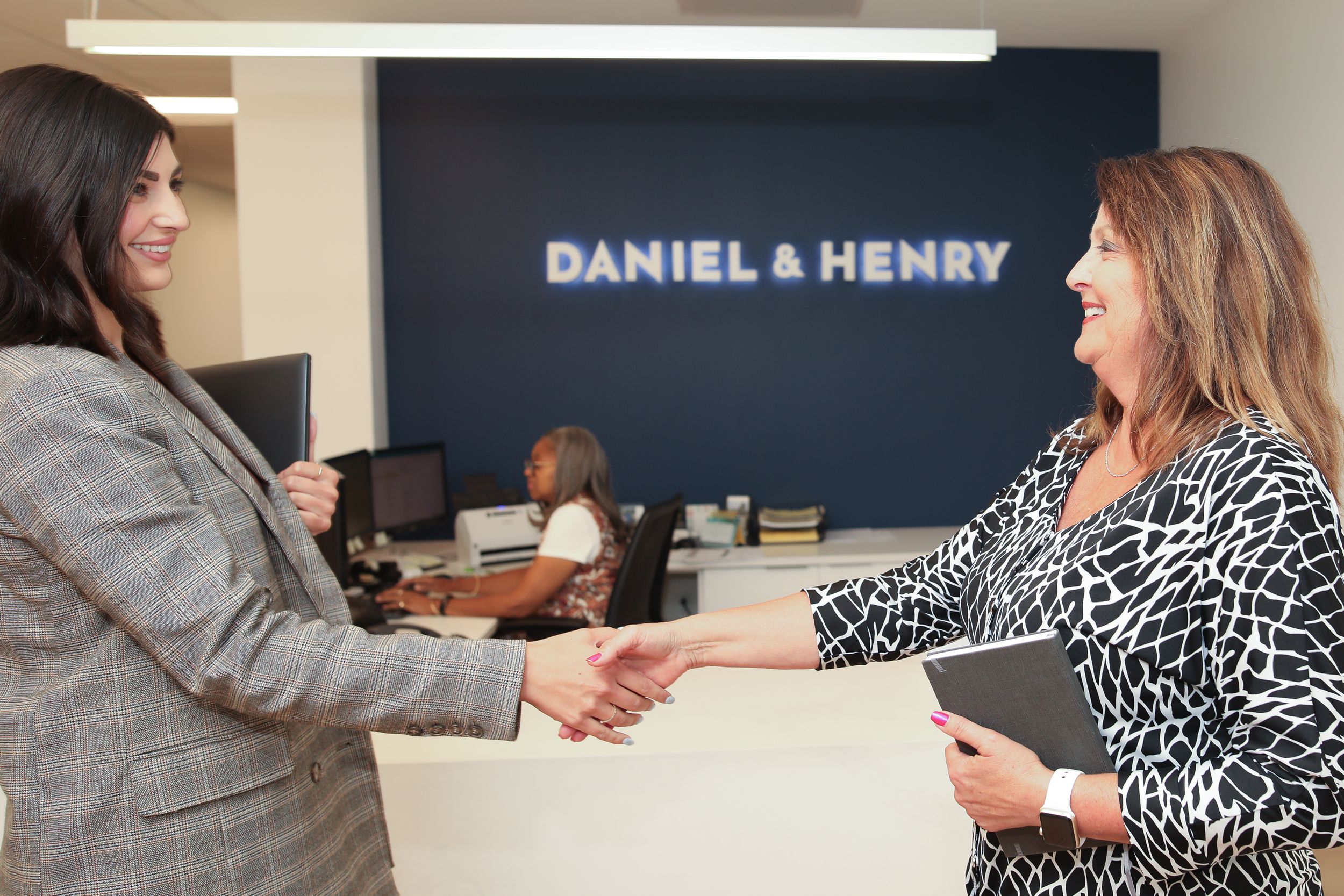 Business meeting at Daniel & Henry office with handshake.