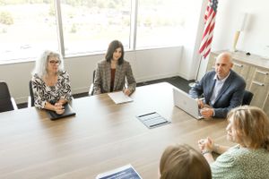Business team meeting in modern conference room with American flag displayed.