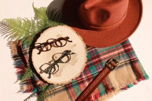 Vintage eyeglasses embroidered on fabric with a brown hat and fern leaf decoration.
