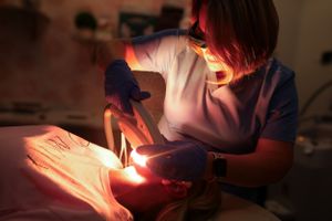 Dental professional using specialized lighting equipment during procedure.