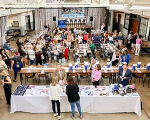 Aerial view of a crowded marketplace with tables and vendors in a large indoor space.