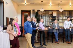 Group of people standing at a modern bar counter during a business event.