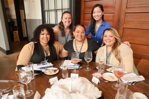 Small group enjoying a meal together at a round table during a professional networking event.