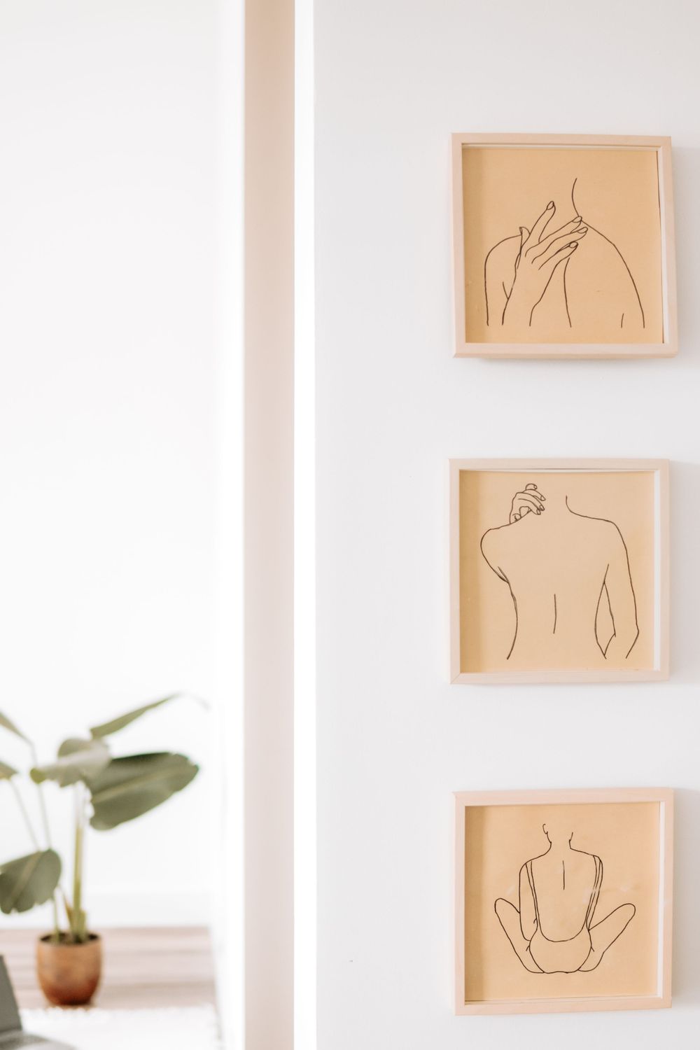 Minimalist wall art featuring three framed line drawings of human figures in beige frames.