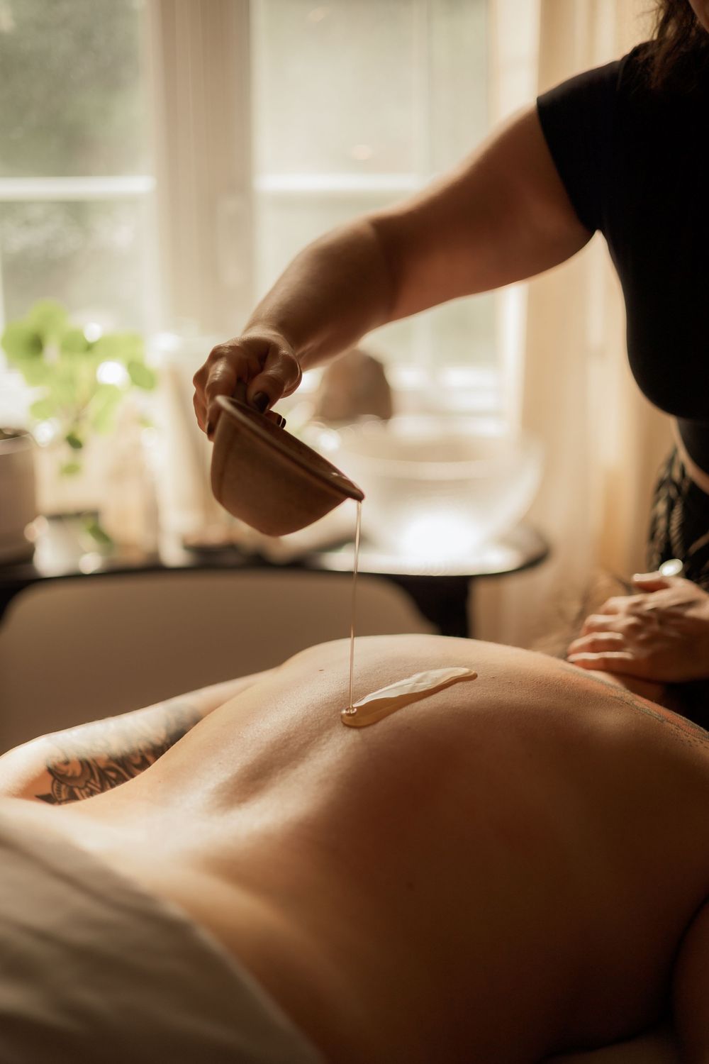 Therapeutic oil being poured onto bare skin during a relaxing massage treatment.