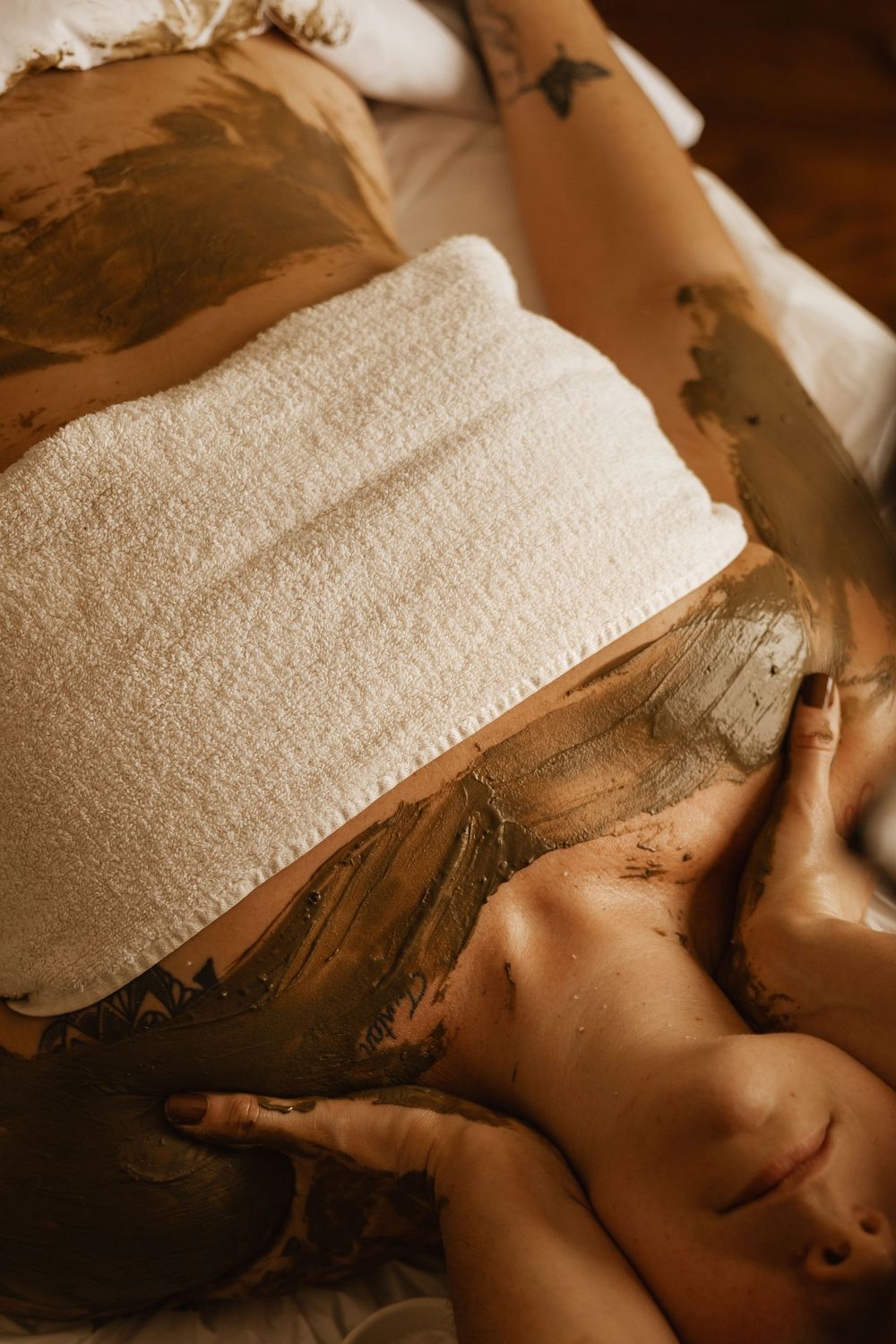 Relaxing spa massage treatment performed with a white towel and oil on a massage table.