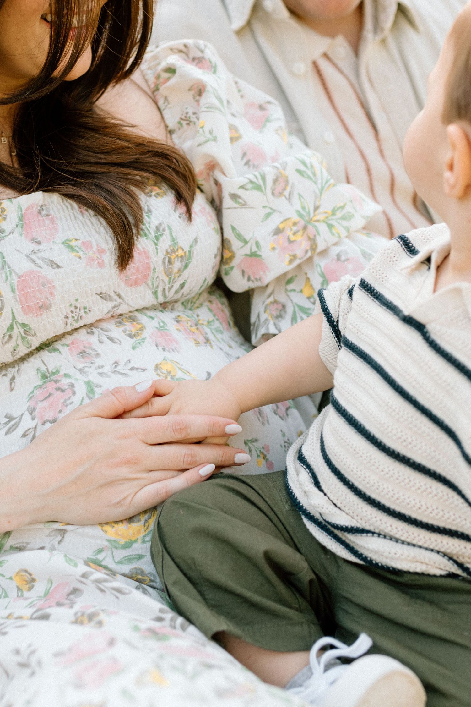 Close-up of floral dress and small child in striped shirt during family photoshoot in San Diego.