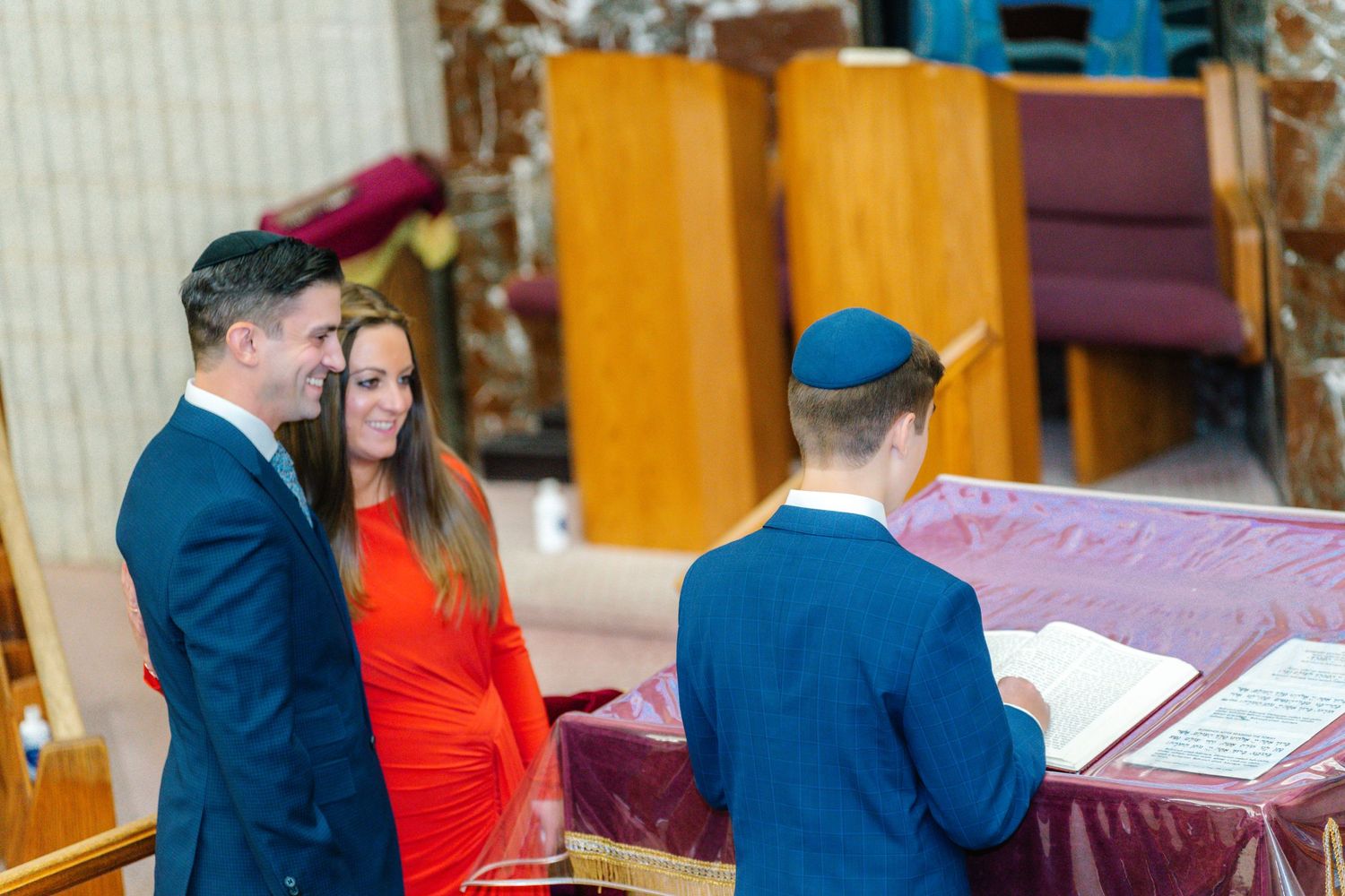 Indoor ceremony scene with formal attire and religious setting.