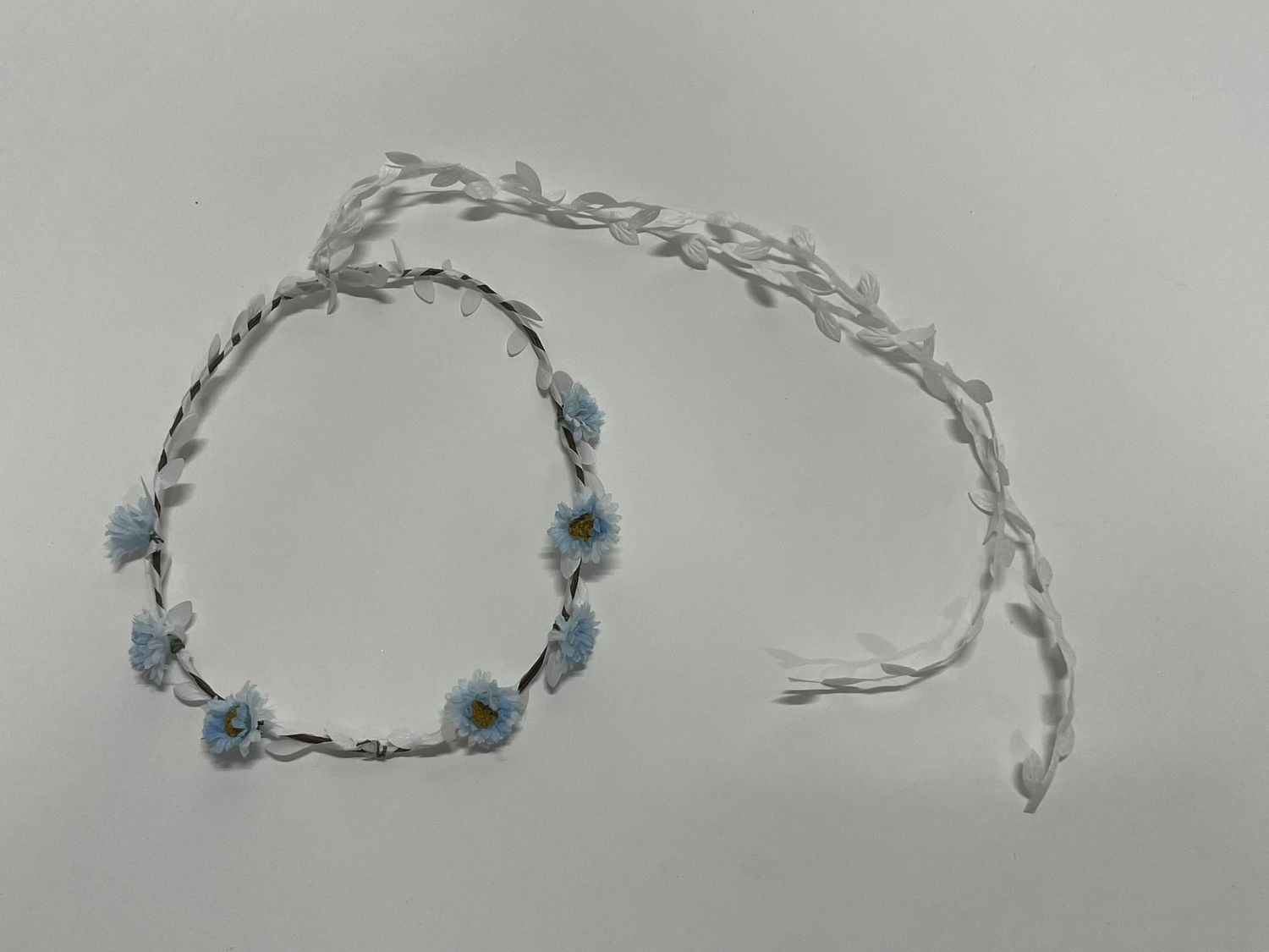 Delicate floral crown with small blue flowers and silver wire twisting around in a circular design.
