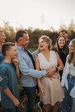 Family sharing genuine laughter during sunset portrait session outdoors.